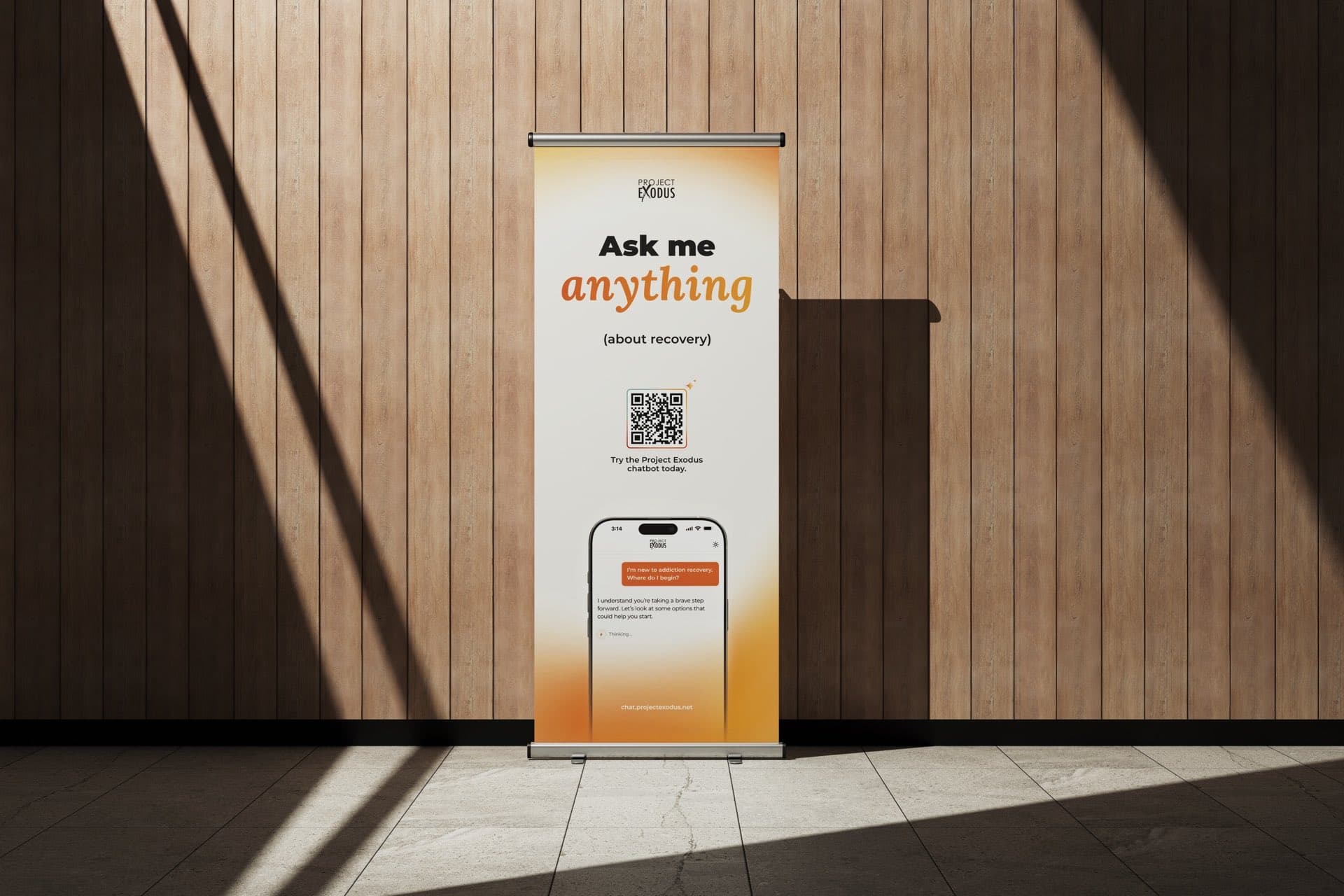 A pull-up banner against a timber wall: Ask me anything, about recovery, with a QR code and a phone showing the chatbot