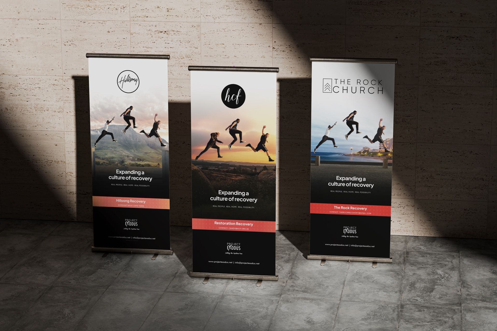 Three pull-up banners side by side, each carrying a different church's logo above the same photograph and line