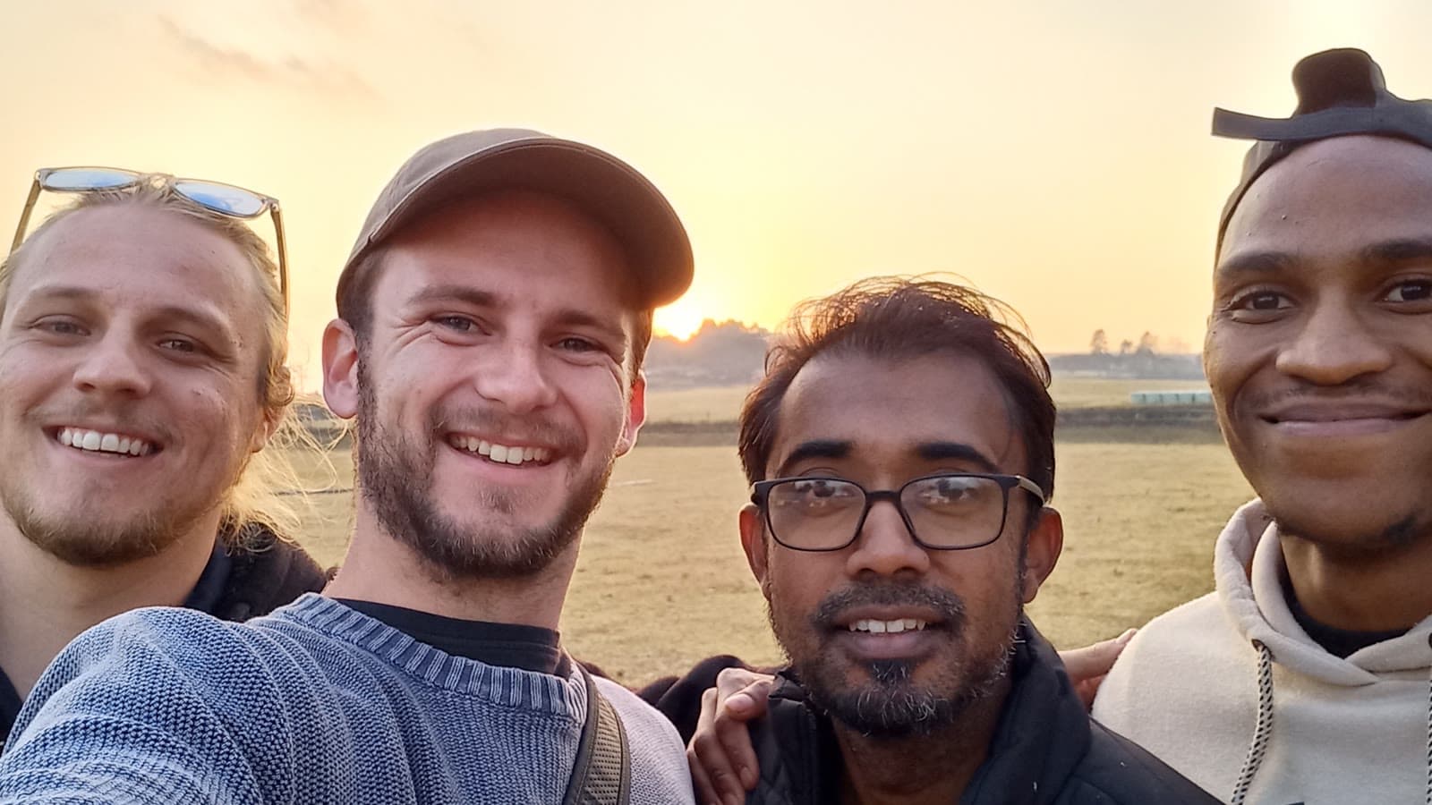 Four crew members at golden hour in a field