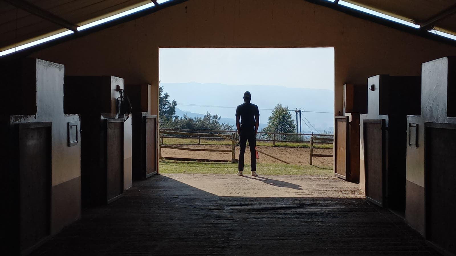 A figure framed in the far doorway of a stable block