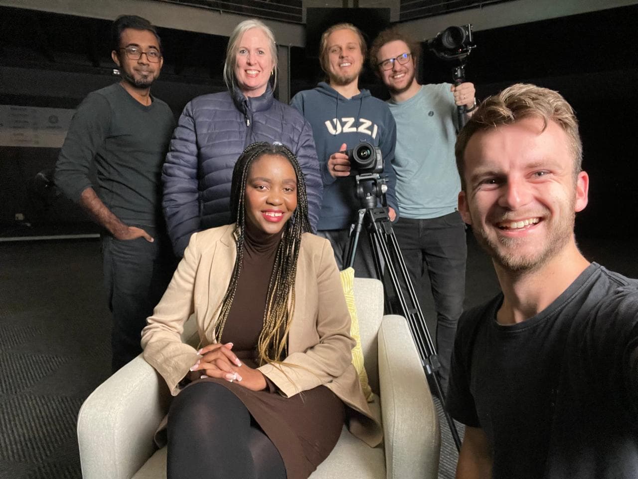 The crew crowded in around the subject for a photo after an interview