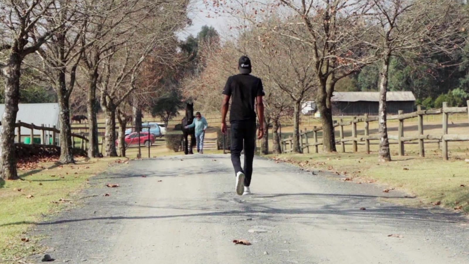 Mpho walking the same tree-lined road in the film
