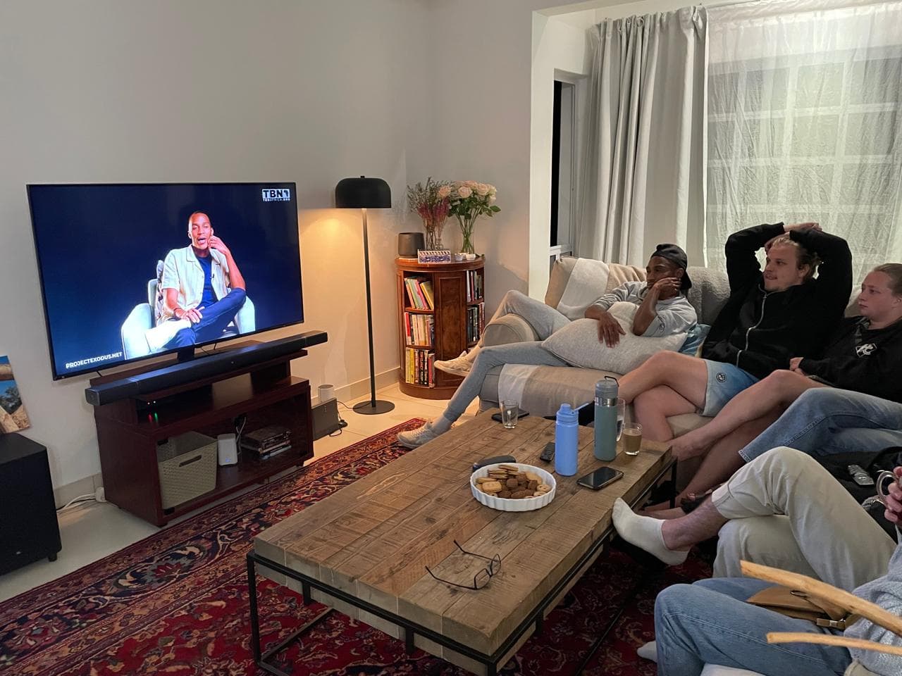 People gathered on couches in a living room, watching the finished film on television